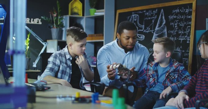 African-American man and group of children studying robotics in laboratory and exploring 3d carton hand. Movement 4K shot on Red cinema camera.
