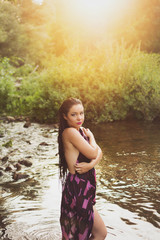Portrait of gorgeous young woman in summer dress standing in water on sunny day