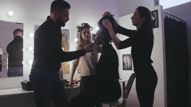 Fashion models together professional stylist and makeup artist in dressing room
