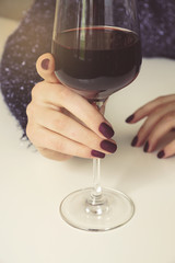 Zhenschina is holding a glass of wine. Soft focus. Toning. Vertical shot. Celebration. The lights of a sun.