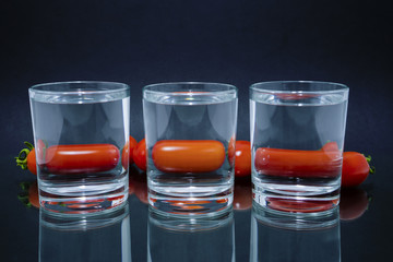cherry tomatoes through three glasses with water on the glass
