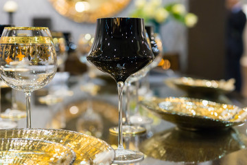 Close up of black and with a golden rim luxurious glasses near plates