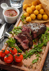 Juicy tasty grilled fillet steak served with tomatoes and cheese balls  on an old wooden board.