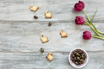 Close-up of cute bunny and butterflies cookies with red tulips flowers on grey vintage background/ Easter and Spring concept