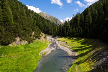 Fototapeta na wymiar Torrente vallaccia flows into lake Lago di Livigno reservoir on border of Italy and Switzerland, Stelvio National Park, beautiful idyllic landscape