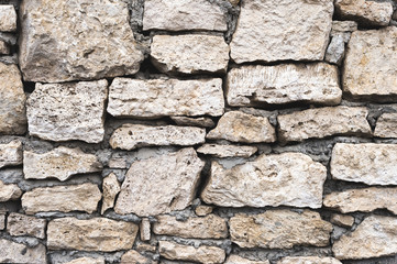 Close-up textured background is an irregular natural stone wall made of different stones without a cement-type bonding mixture. Medieval background