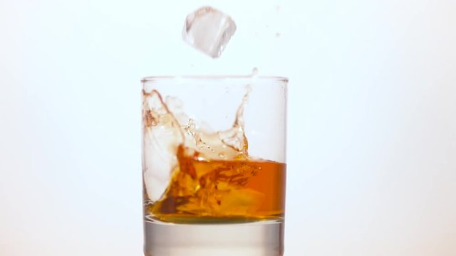 Ice cubes falling into a glass of whisky 