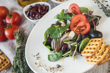 Salad diet for weight correction from the leaves of Lollo Rosso lettuce, watercress salad and other green herbs with tomatoes, olives and fitaki. Close up.