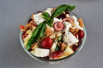 Salad with turkey, apple pieces, fresh cranberry, walnuts, feta cheese,  green basil. Delicious diet food in glass bowl, healthy lifestyle concept. Perfect combination of fresh fruits and meat.
