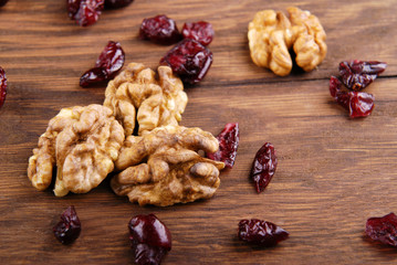 Walnut and dry cranberries on a dark wooden background.