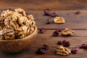 Walnut and dry cranberries on a dark wooden background.