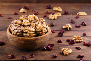 Walnut and dry cranberries on a dark wooden background.