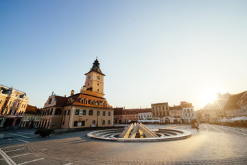 City central square (Piata Sfatului) with town council hall tower, fountain morning sunrise view, location Brasov, Transylvania, Romania. Famous travel destination summer postcard.