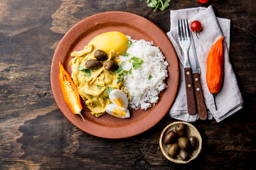 MEXICAN AND PERUVIAN CUISINE. Aji de gallina. Chicken aji de gallina with olives egg and rice on clay plate. Tipical peruvian and mexican dish