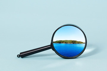An island in the sea under a magnifying glass on a light blue background.