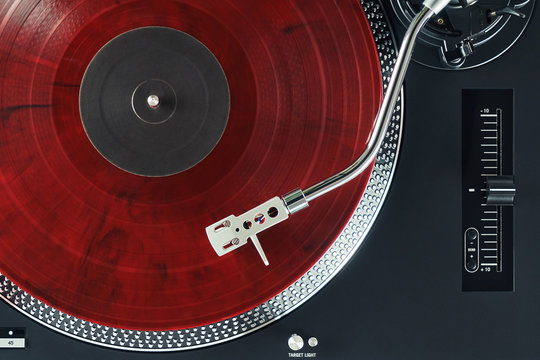 Turntable vinyl record player. Sound technology for DJ to mix & play music. Needle on a vinyl record. Red vinyl record                                                       