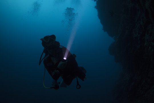Scuba diver diving in the night with torch light