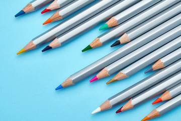 Texture of the school is delivered on a graphite board close-up. Bright colorful pencils on a blue background laid out diagonally. Ready background for design
