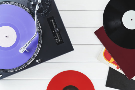 Turntable vinyl record player on the background white wooden boards. Sound technology for DJ to mix & play music. Needle on a vinyl record. Purple vinyl record                    