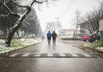 Two guys walking down the street while snowing