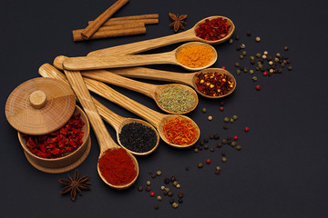 Spice. Spice in a wooden spoon. Herbs. Curry, saffron, turmeric, pepper and others on a black background.