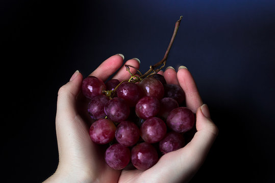A bunch of red grapes, against a dark background