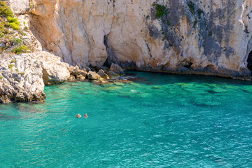 People swimming in the crystal clear water. Porto Limnionas beach on the island of Zakynthos. Greece.