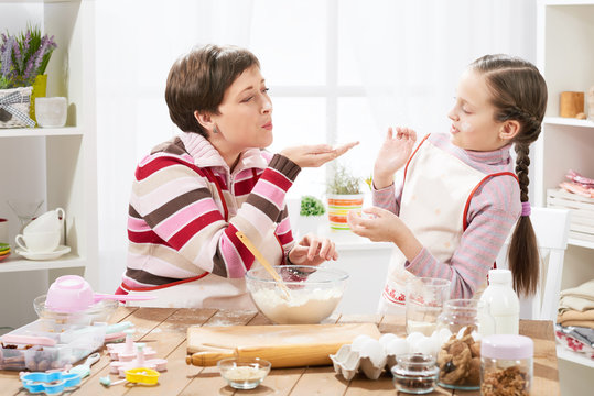 mother and daughter make dough for buns and play with flour, home kitchen interior, healthy food concept