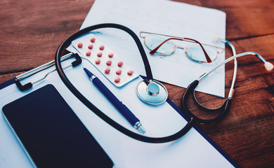 Doctor workplace. Stethoscope with notebook and pencil on the wooden table. Medical concept