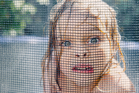 Boy face squished up against trampoline net