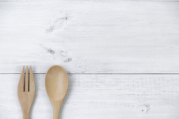 Wooden spoon and fork on white wooden background.