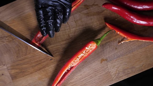 Сhili pepper is cut with a knife. Cutting red hot pepper on cutting board. Close-up, slow motion