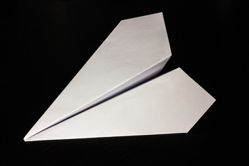 Paper airplane on a dark background for design and flight of fantasies