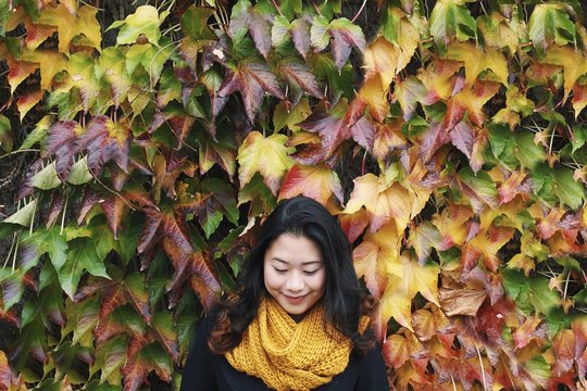 Smiling girl against very colourful leafy wall