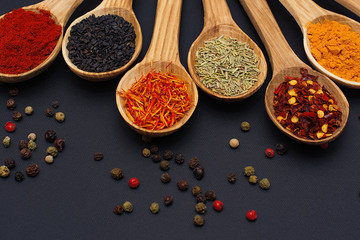 Spice. Spice in a wooden spoon. Herbs. Curry, saffron, turmeric, pepper and others on a black background.