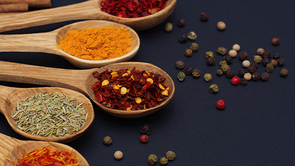 Spice. Spice in a wooden spoon. Herbs. Curry, saffron, turmeric, pepper and others on a black background.