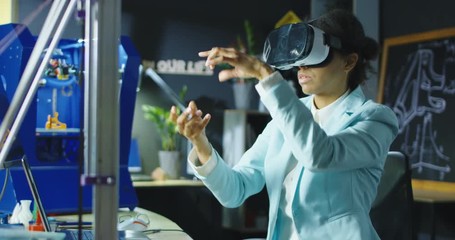 Woman wearing VR headset while working with engineering project in lab with three dimensional printing. Movement 4K shot on Red cinema camera. - Powered by Adobe