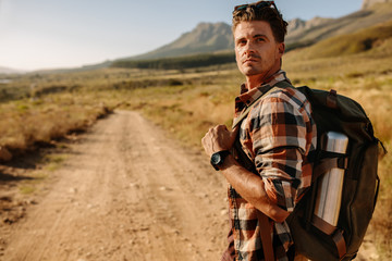 Young man with backpack walking on hiking trail