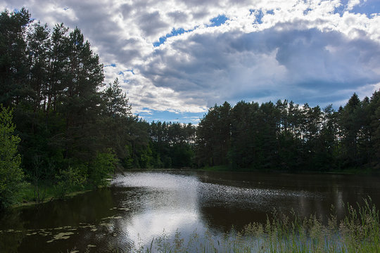 Desktop wallpaper. Background. The lake is shrouded in trees. The sky with clouds. Nature.