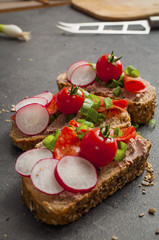 sandwich with vegetables and salami on a black table, healthy food. 
