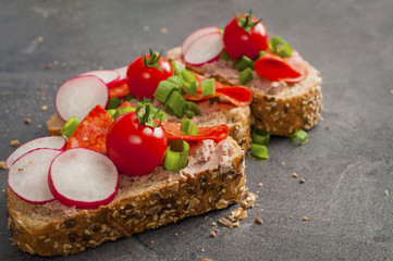 sandwich with vegetables and salami on a black table, healthy food. 