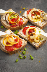 sandwich of spicy salami and cheese on a black wooden table.