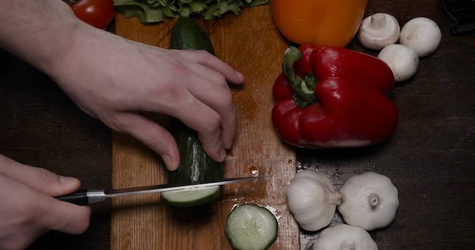 Kitchen table with vegetables, cucumber, red, yellow pepper, tomato, green salad, champignons, garlic knife....