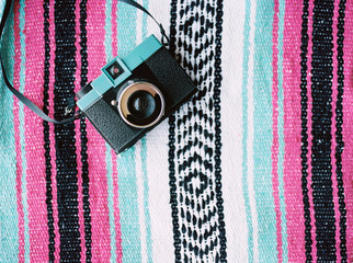 A colorful film camera on a beach blanket.