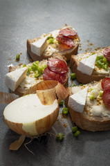 sandwich of spicy salami and cheese on a black wooden table.