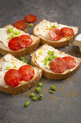 sandwich of spicy salami and cheese on a black wooden table.