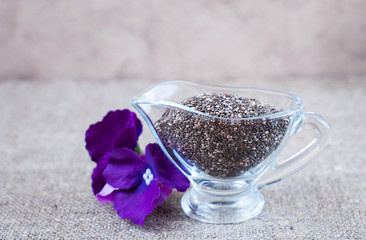 Chia seeds in glassware with purple flowers on a linen tablecloth