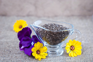 Chia seeds in glassware with purple and yellow flowers on a linen tablecloth