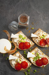 sandwich of spicy salami and cheese on a black wooden table.