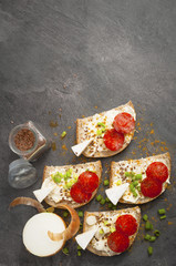 sandwich of spicy salami and cheese on a black wooden table.